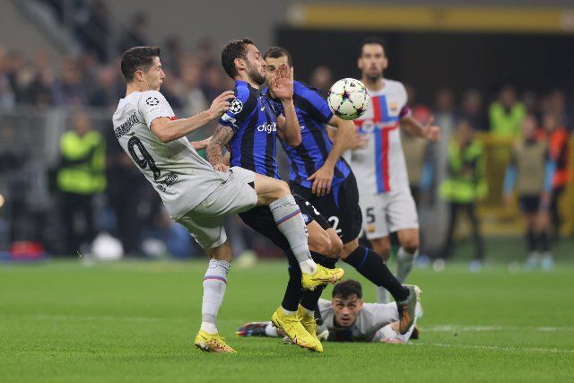 October 4, 2022, Milan, United Kingdom: Milan, Italy, 4th October 2022. Robert Lewandowski of FC Barcelona challenges Hakan Calhanoglu of FC Internazionale as Pedri of FC Barcelona looks on from the deck during the UEFA Champions League Group C match at Giuseppe Meazza, Milan