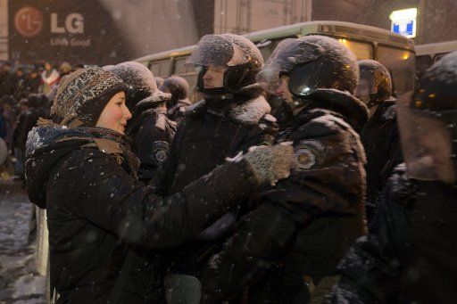 A Ukrainian oppostition activist hugs policemen who have restricted the access to Independence Square, in Kiev, Ukraine, 09 December 2013. Demonstrations against President Yanukovych and for a convergce with the European Union continue in Kiev. ...