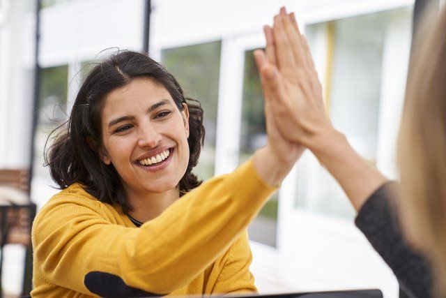 Shot of Latin-American businesswoman high-fiving her co-worker in outdoors office