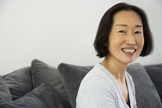 Portrait of Asian-American senior woman smiling and looking at camera while sitting in living room