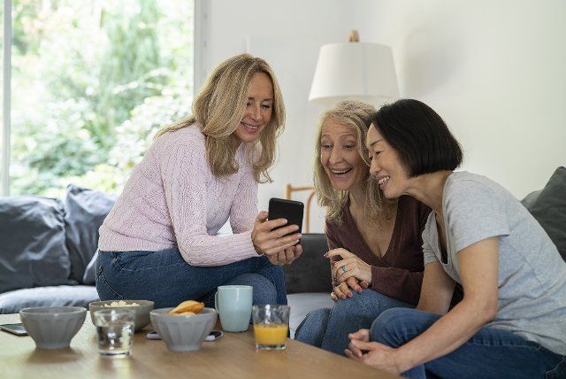 Senior women watching video on smart phone while sitting on sofa