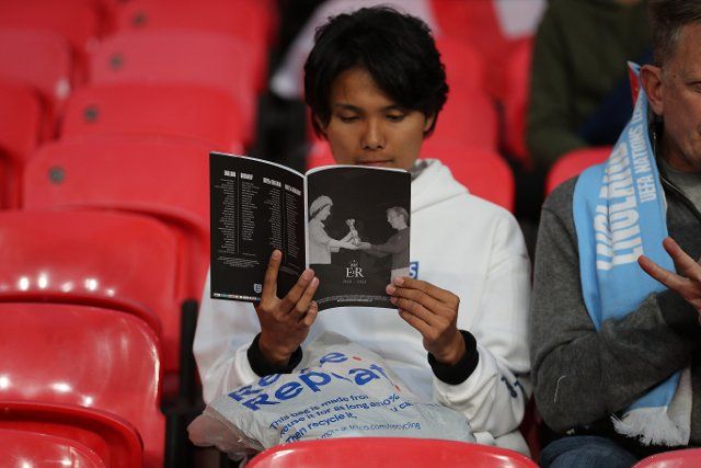 26th September 2022; Wembley Stadium, London, England: UEFA Nations League football, England versus Germany; England fan reading the match programme featuring Queen Elizabeth II handing the 1966 World Cup trophy to England captain Bobby Moore in tribute to for Queen Elizabeth
