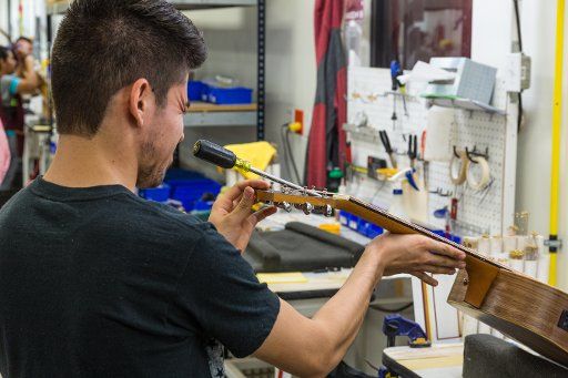 Workers building and assembling guitars at the Taylor Guitar factory in Tecate, Mexico. This worker is adjusting the truss rod in the guitar neck