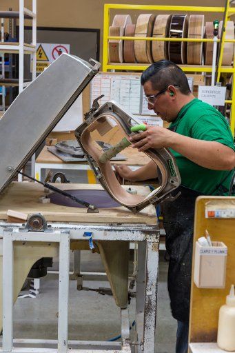 Worker building and assembling guitars at the Taylor Guitar factory in Tecate, Mexico. This worker is gluing the halves of the guitar body together