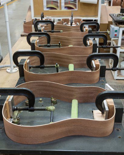 Guitar bodies are glued together and clamped in the Taylor Guitar factory in Tecate, Mexico