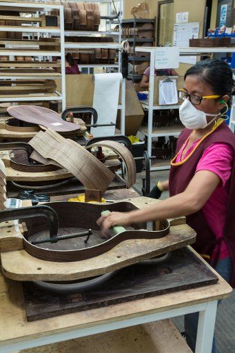 Workers building and assembling guitars at the Taylor Guitar factory in Tecate, Mexico. This worker is gluing the halves of the guitar body together