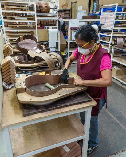 Workers building and assembling guitars at the Taylor Guitar factory in Tecate, Mexico. This worker is gluing the halves of the guitar body together