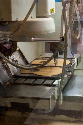 A computer-controlled CNC precision milling machine cuts out a guitar in the Taylor Guitar factory in Tecate, Mexico