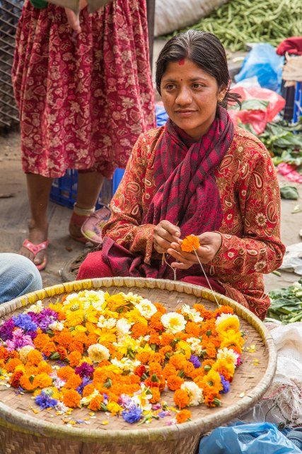 A young Nepali woman making flower garlands for religious offerings at Hindu temples in Kathmandu, Nepal