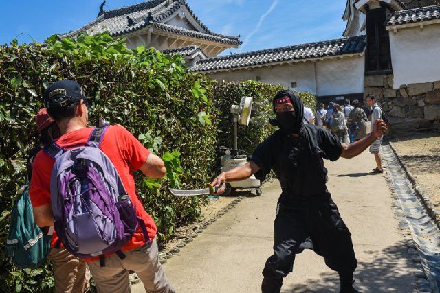 A man dressed as a ninja welcomes tourists to Himeji Castle (HimejijÅ), also known as White Heron Castle, is Japanâs best preserved feudal