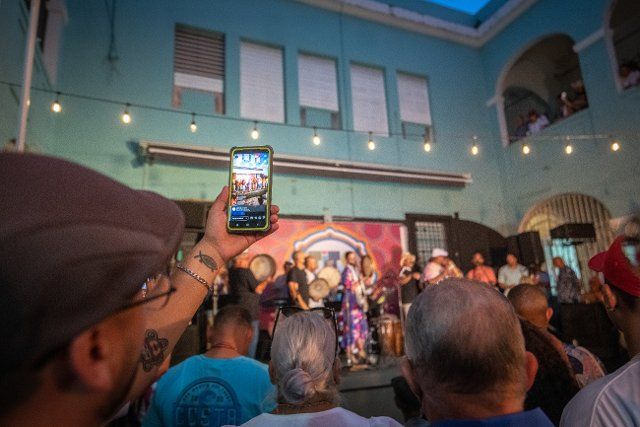 Audience member recording Bomba and Plena performance on smartphone at Tito Matos