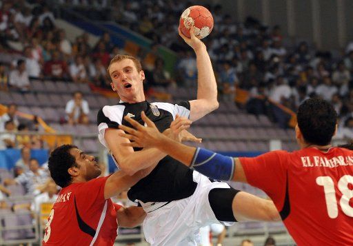 Peking 2008 - Handball Deutschland - Ägypten Holger Glandorf (M) of Germany vies with Mohamed Ramadan (L) and Hany El Fakharany of Egypt during the preliminary round match Germany against Egypt in the OSC Gymnasium in the menÒs Handball competition ...