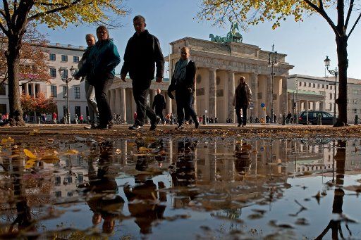 Tourists walk past a puddle reflecting the Brandenburg Gate in berlin germany 18 October 2010. Photo: ROBERT 