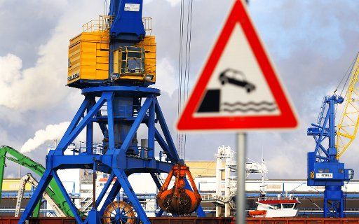 Harbour cranes stand at the port next to a traffic sign that warns of driving into the water in Wismar Germany 29 November 2010. Photo: Jens