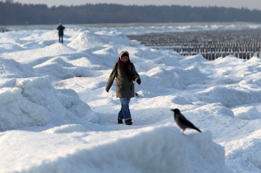People take walks on metre-high piles of snow and ice at the beach Zingst at the Baltic Sea Germany 05 Janbuary 2011. Shortly before thaw prevails in Germany the winter landscape shows itself at its best. Photo: Bernd