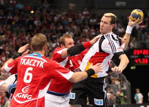German Pascal Hens (R) Polish player Artur Siodmiak (C) and Grzegorz Tkaczyk (L) vie for the ball during the international handball match Germany vs Poland at the Lanxess-Arena in Cologne Germany 08 December 2010. Photo: OLIVER 