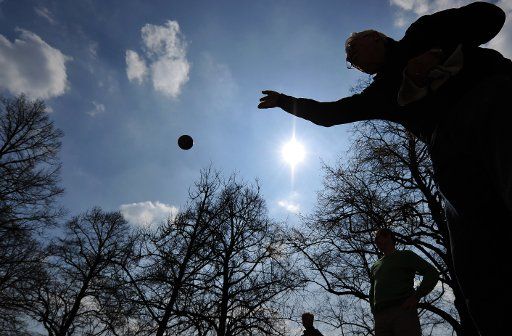 A Boules player throws his metallic ball into the air in the Hofgarten (court garden) in Munich Germany 29 March 2011. Rising temperatures attracted people to visit the gardens of the Bavarian state capital. Photo: PETER