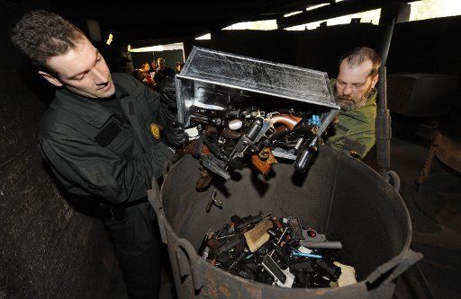 A file picture taken on 30 March 2009 shows employees of an explosives removal squad who melt weapons into an oven in Sindelfingen Germany. Weapons that were turned in also subsequent to a call after the amok shooting in Winnenden and Wendlingen ...