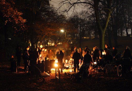 Parents and children stand around a fire in a park with their colorful lanterns after a lantern procession in Hamburg Germany 10 November 2011. Photo: Christian
