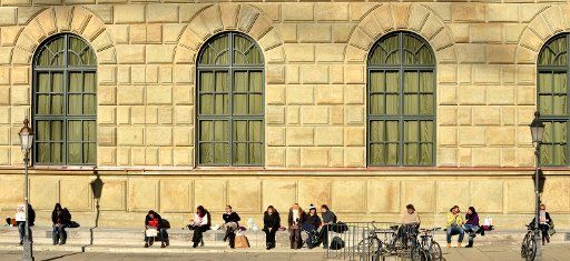 Pedestrians sit in the winter sun in front of the Residenz in Munich, Germany, 18 January 2012. Photo: Frank