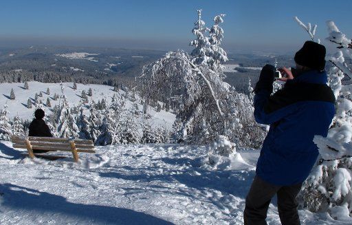 A man takes a picture of his wife on top of the 1,493-meter-high snow-covered Feldberg, Germany, 06 February 2012. Photo: Roland
