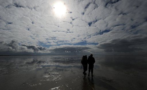 People talk a walk along mudflats on a clouds day in Dagebuell, Germany, 13 April 2012. The weather in the north of Germany shall get better, with temperatures around 14 degrees Celsius. Photo: CARSTEN