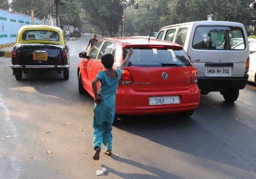 A begging street child runs after a red Volkswagen Polo in Delhi, India, 23 November 2012. Photo: Jens