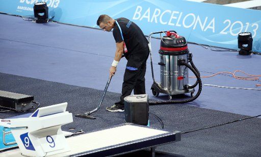 An assistant cleans the floor ahead of the 15th FINA Swimming World Championships at Palau Sant Jordi Arena in Barcelona, Spain, 19 July 2013. Photo: Friso Gentsch\/dpa +++(c) dpa - Bildfunk+++