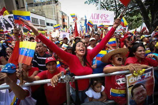 07 August 2019, Venezuela, Caracas: Supporters of the government of President Maduro shout political slogans at a rally against the new U.S. sanctions. In addition to existing sanctions against individuals and government agencies, US President Trump had frozen all assets of the Maduro government in the US with immediate effect. The Venezuelan government has sharply criticized the new US sanctions and described them as "terrorism". Photo: Boris Vergara\/
