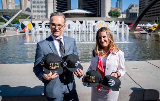 14 August 2019, Canada, Toronto: Heiko Maas (SPD), Foreign Minister, and Chrystia Freeland, Foreign Minister of Canada, hold caps of the NBA basketball team Toronto Raptors with the inscription "We the Champs" in their hands. Maas is in Canada for political talks. Photo: Kay Nietfeld\/