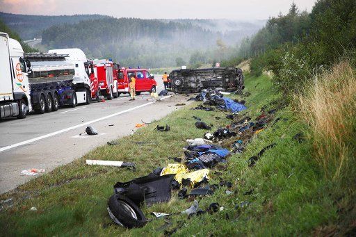 30 August 2019, Thuringia, Bad Lobenstein: Debris is lying on the side of the Autobahn 9 at an accident site, in the background there is a vehicle on the side, emergency personnel are standing on the road. In the afternoon, a small truck drove between Bad Lobenstein and Schleiz into a group of three motorcycles occupied by four people who had probably sought shelter from the rain under a bridge. The motorcyclists died at the scene of the accident. (Zu dpa: "Four dead motorcyclists in a serious accident on the A9") Photo: Bodo Schackow\/dpa-Zentralbild\/