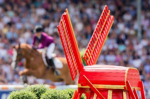 21 July 2019, North Rhine-Westphalia, Aachen: CHIO, equestrian sport, jumping, Grand Prix of Aachen: The rider Luciana Diniz from Portugal on the horse Fit for Fun jumps over an obstacle - in the foreground you can see a model of a windmill. The European Equestrian Games will take place in Rotterdam from 19 to 25 August 2019. Photo: Rolf Vennenbernd\/