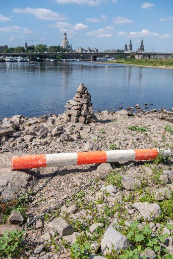 23 July 2019, Saxony, Dresden: A buoy lies on the dry river bed of the Elbe in front of the historical old town scenery with the Frauenkirche (l-r), the Kunstakedmie, the Hausmannsturm and the Semperoper. Due to construction work under the Albert Bridge, the water is diverted at this point. The level of the Elbe in Dresden is currently 69 centimetres. Photo: Robert Michael\/dpa-Zentralbild\/