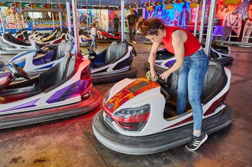 22 July 2019, Hamburg: Mandy Friedrich, employee, cleans a bumper car on the "Autoscooter Stardust" layout at the Hamburg Summer Cathedral 2019. The Volksfest opens its doors on 26 July 2019. Photo: Georg Wendt\/