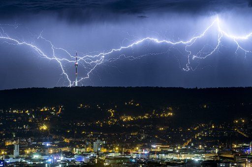 27 July 2019, Stuttgart: Lightnings twitch at night behind the illuminated city on the horizon, and strike near the television tower. In the Stuttgart area it thundered in the night to Saturday, the 27.07.2019 violently. Photo: Simon Adomat\/