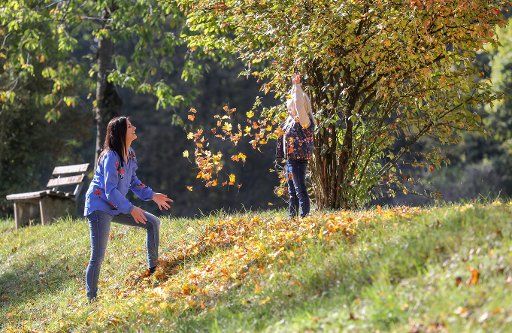 13 October 2019, Baden-Wuerttemberg, Altheim: Jule and her mother throw colourful autumn leaves to each other. Photo: Thomas Warnack\/