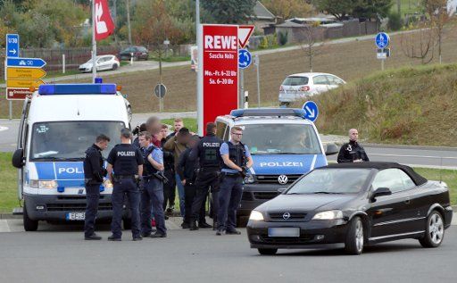 20 October 2019, Thuringia, Leinefelde-Worbis: Suspects are standing in the parking lot of a supermarket between policemen. A violent clash in broad daylight in a supermarket between two hostile groups has led to a large-scale police operation in Worbis. According to Sunday\