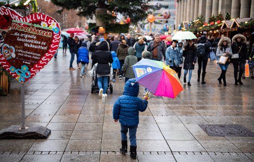 29 November 2019, Baden-Wuerttemberg, Stuttgart: A child walks over the Stuttgart Christmas market with a colourful umbrella. Photo: Tom Weller\/