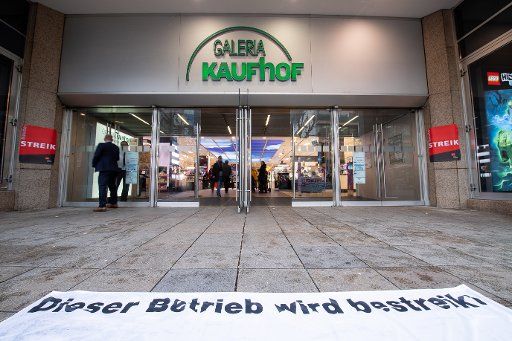 12 December 2019, Baden-Wuerttemberg, Stuttgart: During a strike by Kaufhof and Karstadt employees, a poster with the inscription "This company is operated" is displayed in front of the logo of a Galeria Kaufhof. Photo: Sebastian Gollnow\/