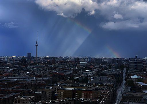 28 September 2019, Berlin: A rainbow stands before a dark sky over Berlin, the Berlin television tower can be seen on the horizon. Photo: Paul Zinken\/