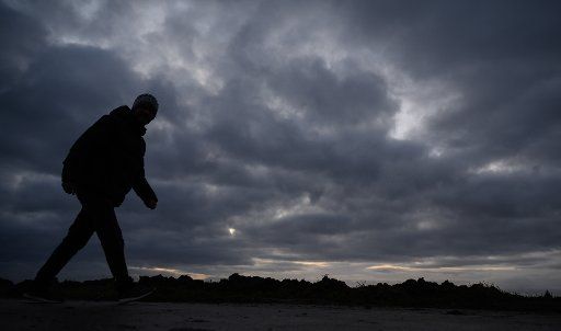 29 January 2020, Baden-Wuerttemberg, Filderstadt: A man walks in front of dark, low-hanging clouds. Photo: Sebastian Gollnow\/