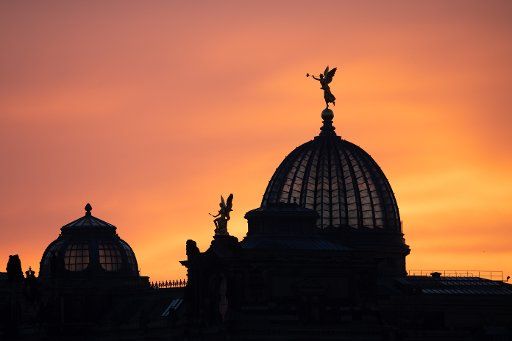 20 December 2019, Saxony, Dresden: The sun rises behind the dome of the exhibition hall of the art academy with the gilded trombone angel Fama. Photo: Sebastian Kahnert\/dpa-Zentralbild\/