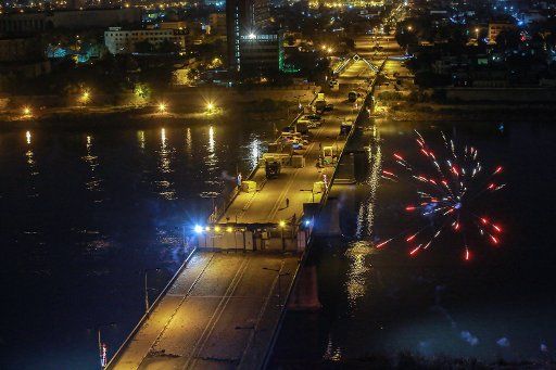 31 December 2019, Iraq, Baghdad: Fireworks burst above Al-Jumhuriya Bridge near Tahrir Square where people gathered to celebrate the 2020 New Year\