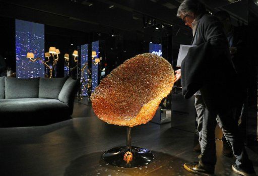13 January 2020, North Rhine-Westphalia, Cologne: A fair visitor looks at an illuminated glitter armchair (manufacturer: Edra). The furniture fair will take place from 13 to 19.01.2020 in Cologne. Photo: Oliver Berg\/