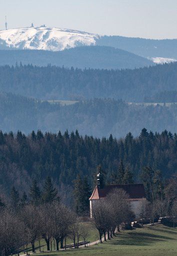 25 March 2020, Baden-Wuerttemberg, St. Märgen: The Ohmenkapelle stands in front of the snow-covered Feldberg in the sun. Photo: Patrick Seeger\/