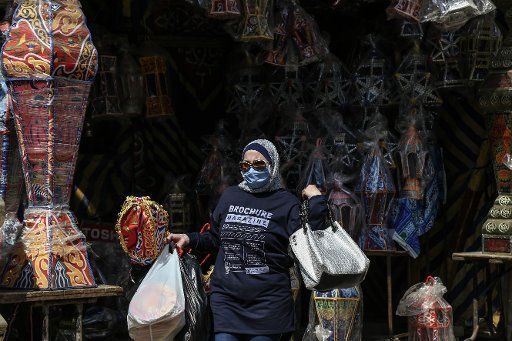 12 April 2020, Egypt, Cairo: A woman wearing a face mask walks at the Khayameya Street in old Cairo, which is famous for selling Ramadan lanterns (Fanous) ahead of Islam\