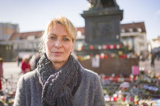 25 February 2020, Hessen, Hanau: Silke Hoffmann-Bär, victim representative of the city of Hanau, is standing on the market place at the monument of the Brothers Grimm, where the citizens express their grief with flowers, posters and candles. One week ago, on 19 February 2020, a 43-year-old German man shot several people and himself in an alleged racist attack. Photo: Frank Rumpenhorst\/dpa\/Frank Rumpenhorst\/