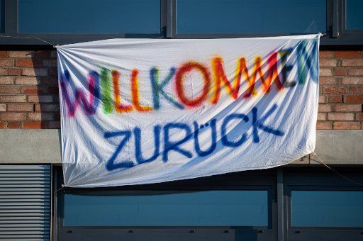 18 May 2020, Saxony, Dresden: A bed sheet that says "Welcome back" is hanging from a school. From this Monday on, primary and secondary schools will open their doors again after weeks of compulsory Corona break. Photo: Robert Michael\/dpa-Zentralbild\/