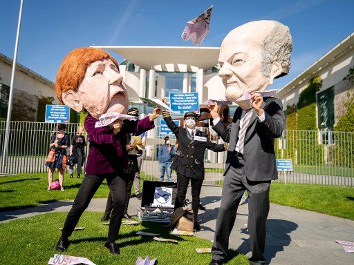27 May 2020, Berlin: Activists of the campaign organisation Campact protest in front of the Federal Chancellery with posters and masks with the counterfeits of Chancellor Merkel and Federal Finance Minister Scholz against a Lufthansa rescue without conditions. Photo: Kay Nietfeld\/