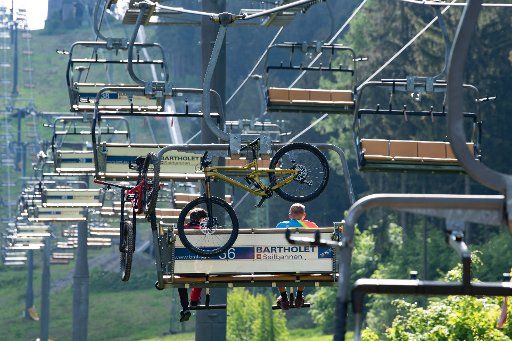 27 May 2020, Lower Saxony, Goslar-Hahnenklee: Two cyclists are sitting with their mountain bikes in the chairlift on the Bocksberg in the Harz Mountains and are transported to the Hahnenklee Bikepark. Photo: Swen Pförtner\/
